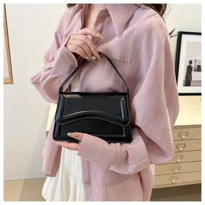 Detail of black vintage handbag with unique wavy textured flap and elegant top handle