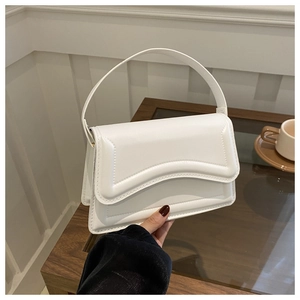 Detailed view of white leather handbag featuring geometric stitching and smooth texture
