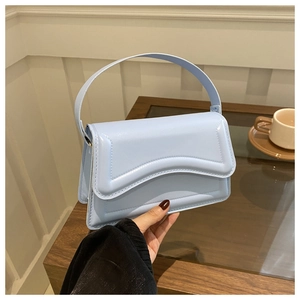 Close-up of a light blue patent leather handbag with wavy stitching and glossy finish