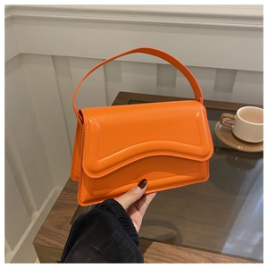 Close-up of bright orange faux leather handbag with unique wave stitching details