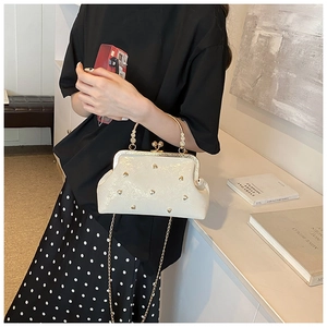 Detail of pearl white leather handbag with golden heart studs and vintage metal handle