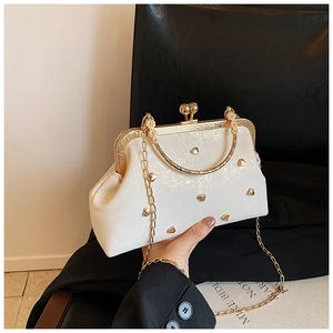 Close-up of pearl white shell bag with golden heart studs and vintage metal clasp