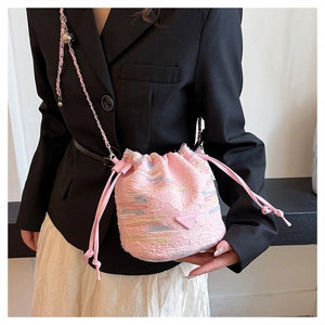 Dettaglio della borsa a secchiello rosa con ricamo colorato e tracolla a catena su modella