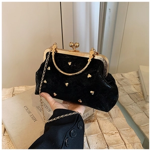 Detail of black velvet handbag with golden heart studs and spherical clasp closure