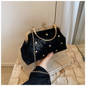 Detail of black velvet handbag with golden heart studs, kiss lock and metal handle