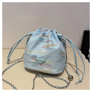 Dettaglio borsa a secchiello azzurra con ricamo a onde colorate e tracolla a catena