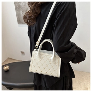 Dettaglio borsa trapuntata bianca con borchie dorate ed elegante tracolla a catena