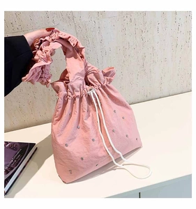 Detailed view of pink drawstring shoulder bag with rhinestones and ruffled handles