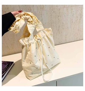 Detailed view of beige pleated tote bag with sparkling rhinestones and drawstring