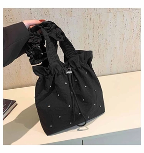 Detail of black tote bag featuring shimmering rhinestones and ruffled shoulder strap
