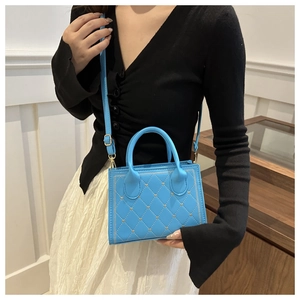 Dettaglio della cucitura trapuntata della borsa in pelle azzurra con tocchi oro