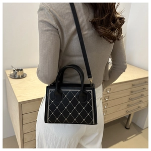 Dettaglio della borsa trapuntata vintage con cuciture bianche e bordi intrecciati su modella