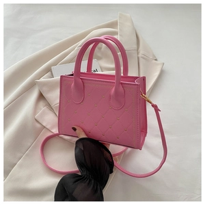 Close-up of pink quilted tote bag with golden heart embroidery and adjustable strap