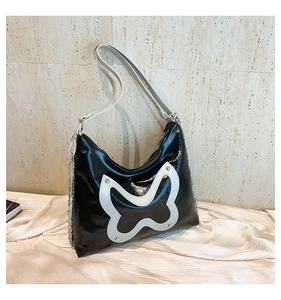Detail of black patent leather shoulder bag with white butterfly patch and silver studs
