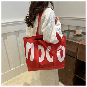 Détail du grand sac cabas rouge avec lettrage noco blanc présenté en intérieur