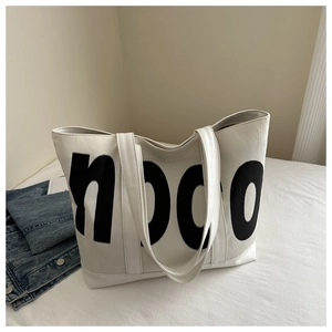 Détail du grand sac cabas blanc avec lettrage noon noir et texture en similicuir