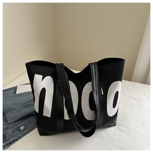 Détail du grand sac cabas noir en toile avec logo blanc et base renforcée en cuir