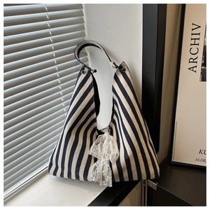 Detail der blau-weiß gestreiften Canvas-Tasche mit dekorativer weißer Spitzenschleife