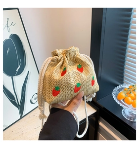Detail of straw bucket bag with strawberry embroidery and drawstring cotton rope