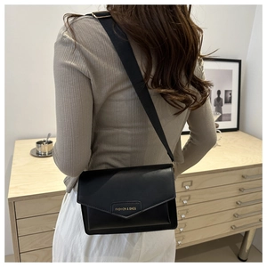Detailed back view of a minimalist black messenger bag with a fashion logo on the flap