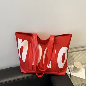Grand sac fourre-tout en nylon rouge avec imprimé lettres blanches sur canapé