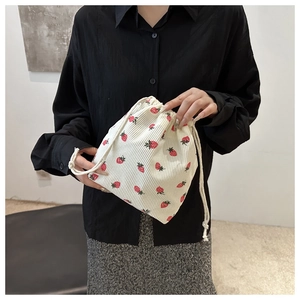 Detail view of corduroy bucket bag featuring red strawberry prints and drawstring closure