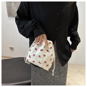 Close-up of a cute strawberry print mini bucket bag with textured corduroy fabric