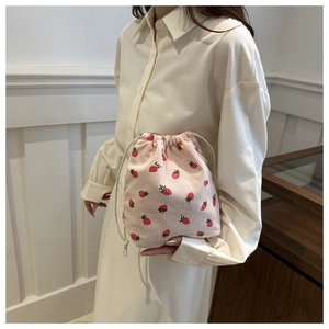 Detail of pink corduroy drawstring bucket bag featuring red strawberry patterns on white dress