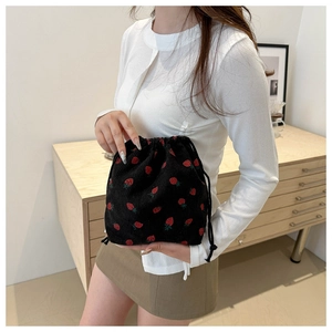 Detail of black corduroy mini bucket bag with strawberry print and drawstring closure