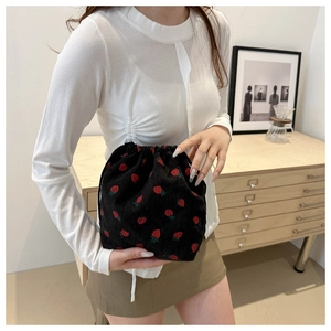 Detail of strawberry print on black corduroy mini bucket bag with drawstring closure