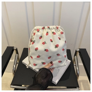 Detail of strawberry print corduroy bucket bag with drawstring closure held in hand