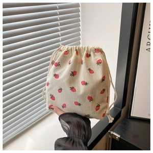 Detail of strawberry embroidery on off-white corduroy mini bucket bag with drawstring closure