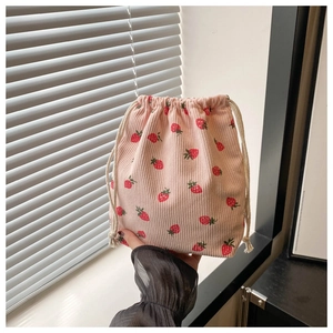 Detail of pink corduroy mini bucket bag with strawberry print and white drawstring closure
