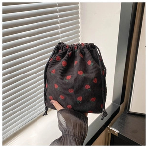 Detail of strawberry print on black corduroy drawstring bucket bag held in hand