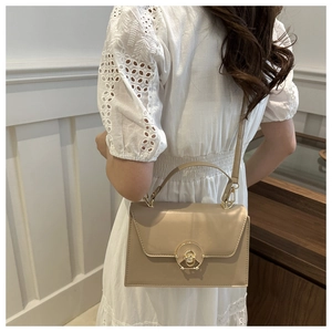 Detail of beige structured handbag with gold ring clasp and matching shoulder strap