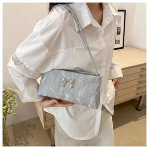 Detail of silver textured shoulder bag featuring a metallic bow and crinkled finish