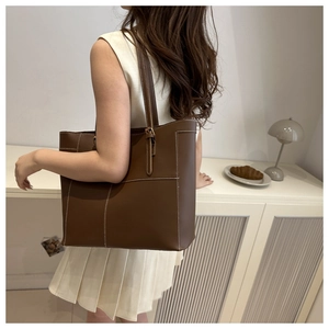 Gros plan d'un sac cabas marron foncé avec coutures blanches contrastées et cuir texturé