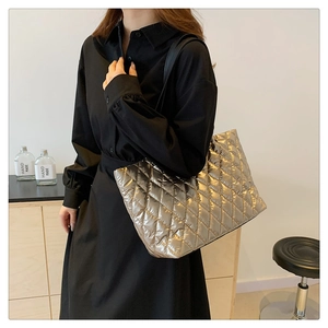 Detail view of large quilted tote bag in metallic gold finish with black shoulder straps