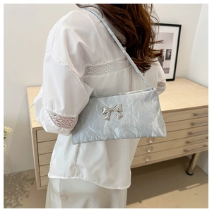 Detail of light blue wrinkled underarm bag with silver bow and metallic finish