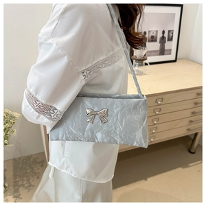 Detail of silver pleated shoulder bag featuring a metallic bow and elegant fabric texture