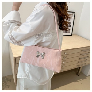 Detail of light pink shoulder bag with a silver metallic bow and pleated texture