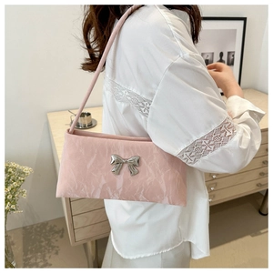 Detail of pink pleated fabric shoulder bag with silver bow hardware and velvet texture
