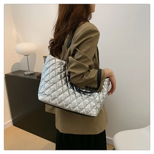 Detail of silver quilted tote bag with metallic finish and chain leather shoulder strap