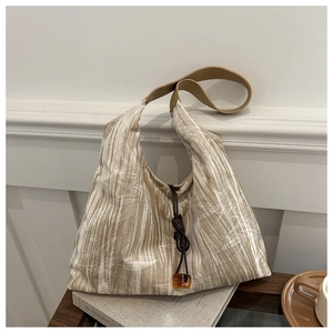 Detail of pleated velvet tote bag with leaf pattern, decorative knot and amber pendant