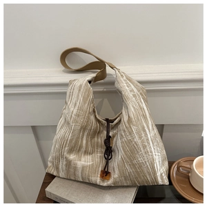 Close-up of beige tote bag with bamboo leaf patterns and amber pendant accessory