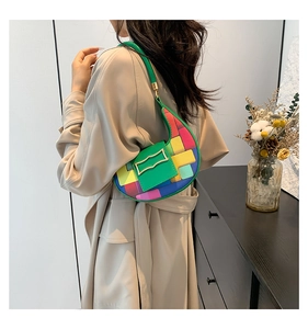 Detail of colorful woven crescent bag with green leather strap and gold buckle