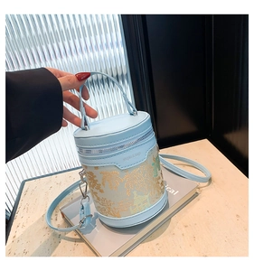Detail of light blue bucket bag with gold floral patterns and jingpin embossed logo