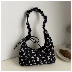 Detail of black floral tote bag with white bow prints and scrunchie shoulder strap