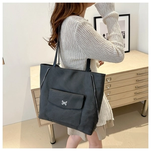 Détail du grand sac cabas noir avec boucle papillon argentée porté par un mannequin