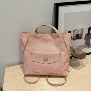 Sac à dos en cuir PU rose avec boucle papillon posé sur une table en bois minimaliste